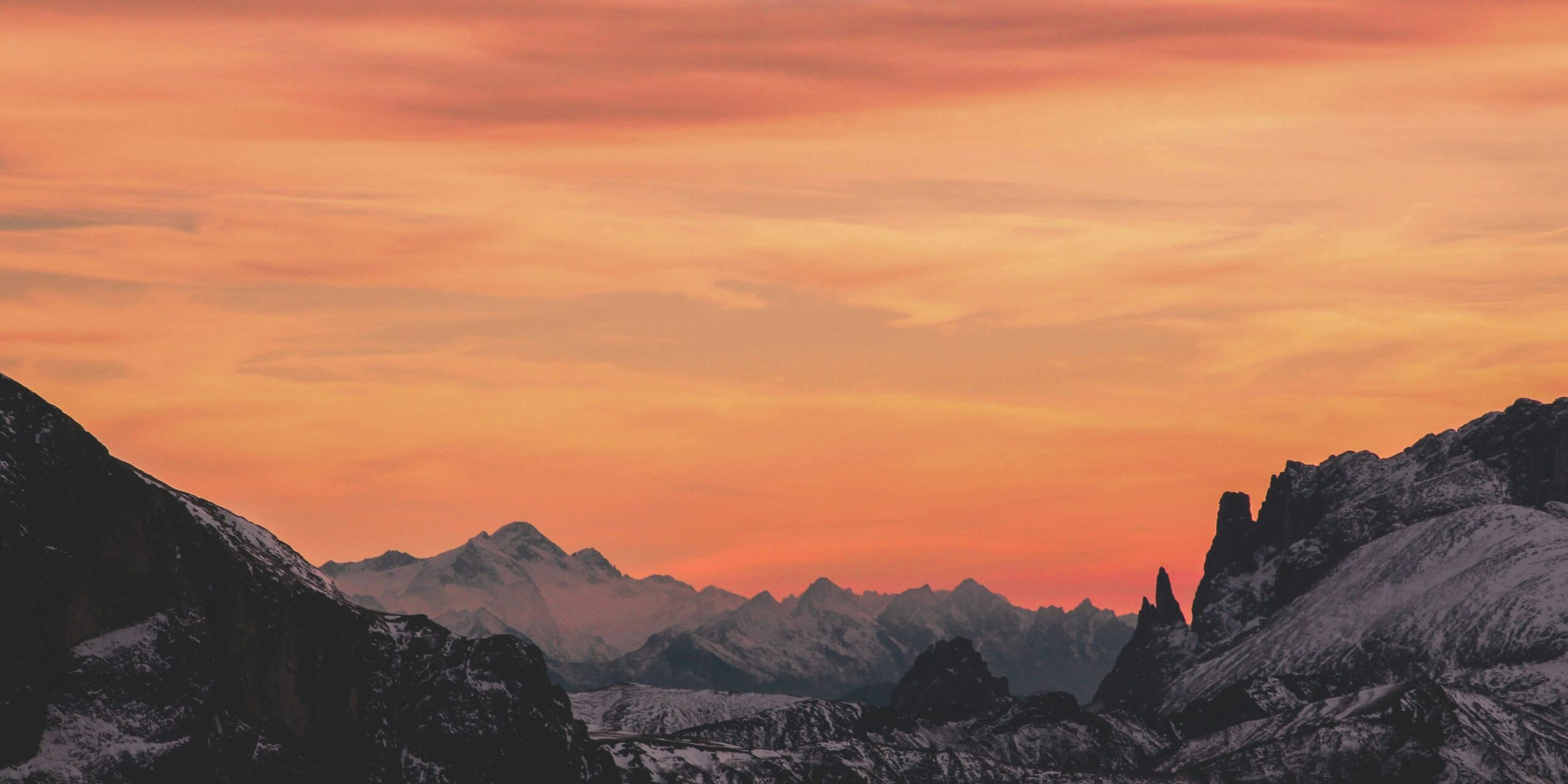 Snowy mountain landscape under an orange sunset sky
