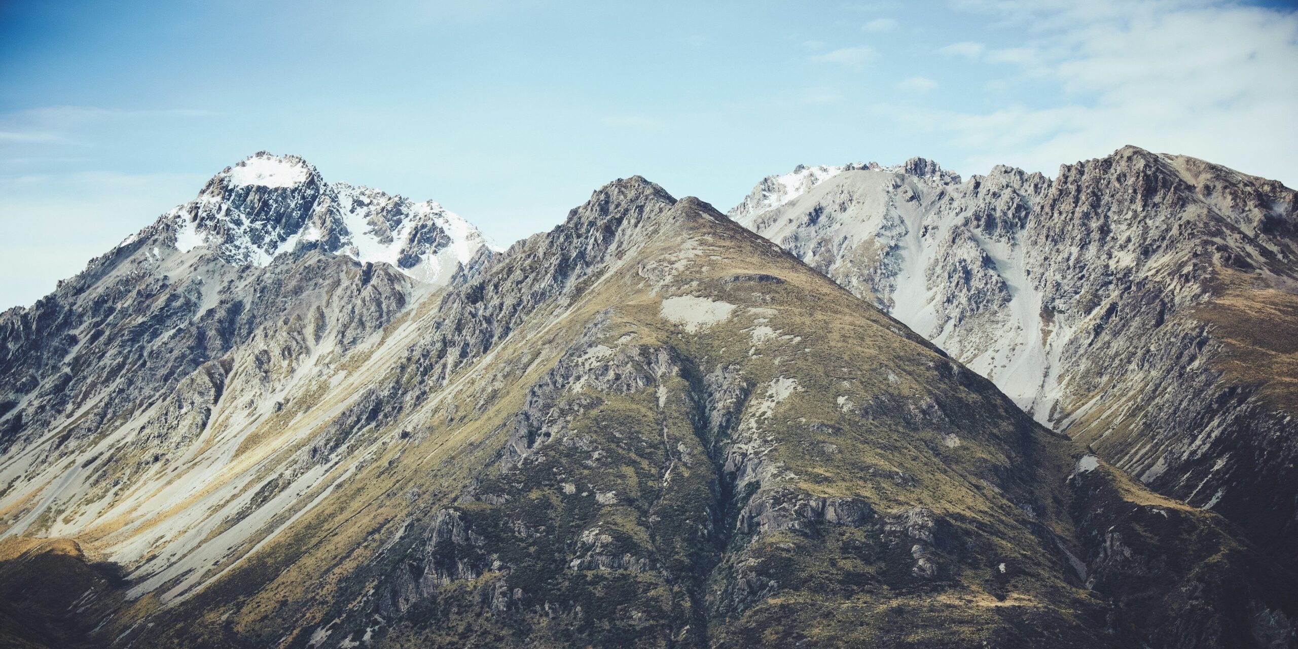 Snow-covered mountain peaks with rugged slopes against a clear blue sky