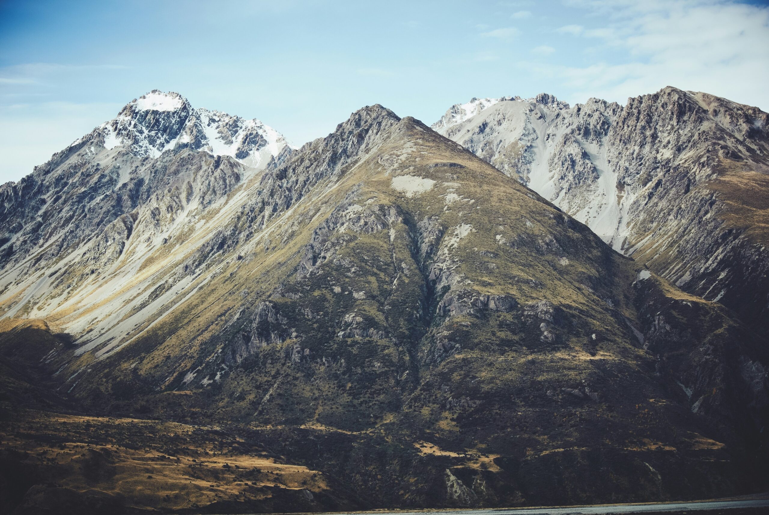 Snow-capped mountain peaks under a clear blue sky with rocky, sloped ridges