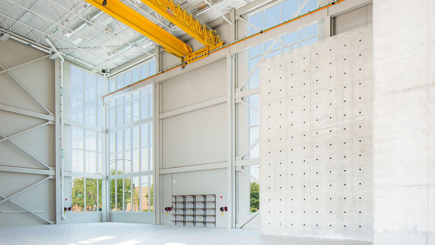 The building features a high-bay structural testing laboratory with a 30-foot high concrete reactive wall and a six-foot-thick concrete strong floor.